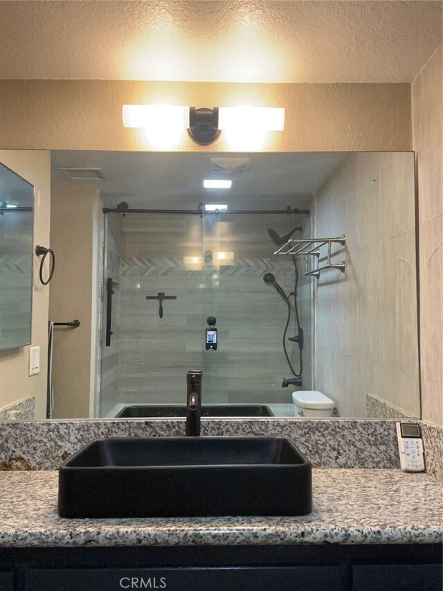 bathroom featuring vanity, an enclosed shower, and toilet