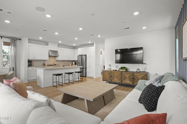 living room with sink and light wood-type flooring