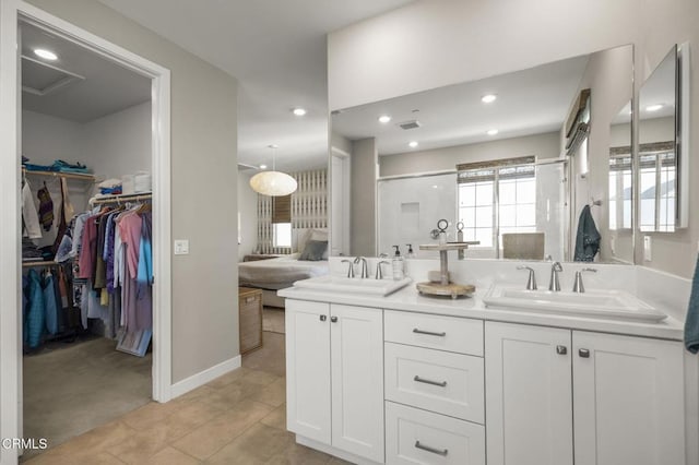 bathroom with a shower with door, vanity, and tile patterned floors