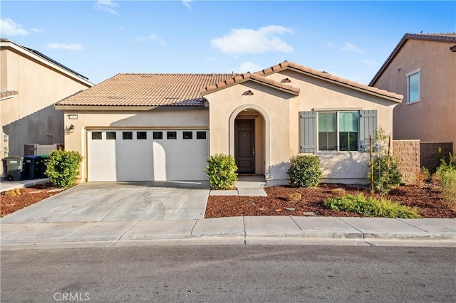 mediterranean / spanish house with a garage, concrete driveway, a tile roof, and stucco siding