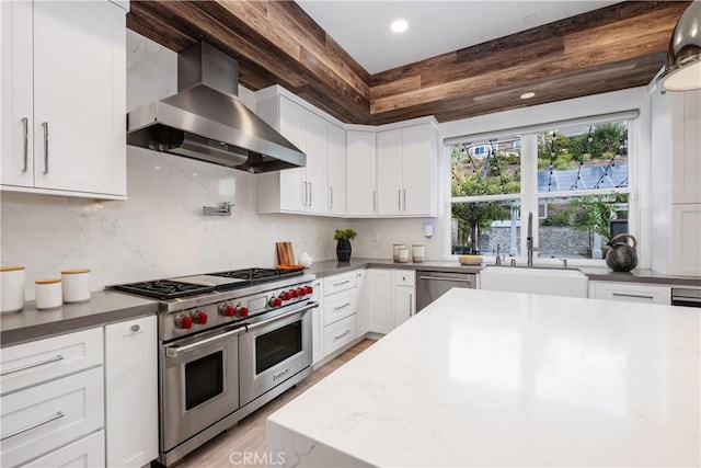 kitchen featuring stainless steel appliances, white cabinets, and wall chimney exhaust hood