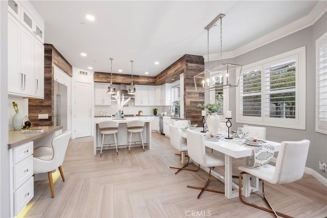 dining room featuring a notable chandelier, crown molding, sink, and light parquet flooring