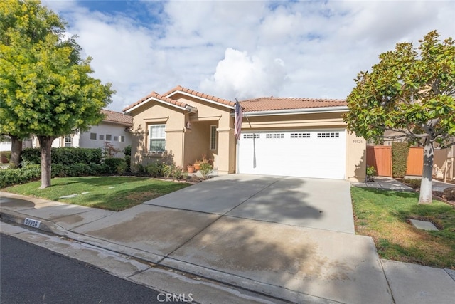 mediterranean / spanish-style house featuring stucco siding, a front lawn, driveway, a garage, and a tiled roof