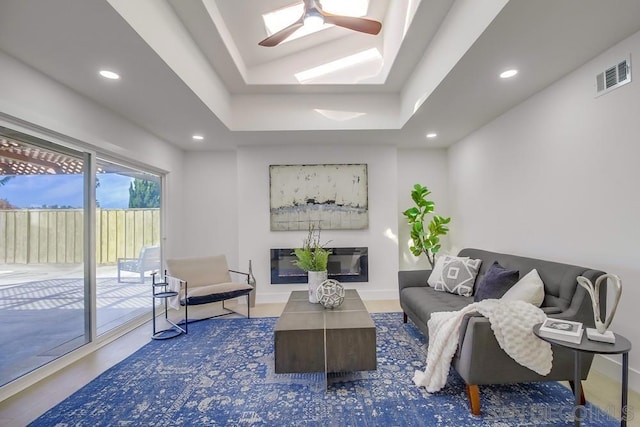 living room with a raised ceiling and ceiling fan