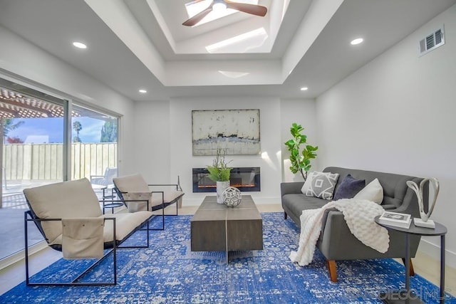 living room with a tray ceiling and ceiling fan