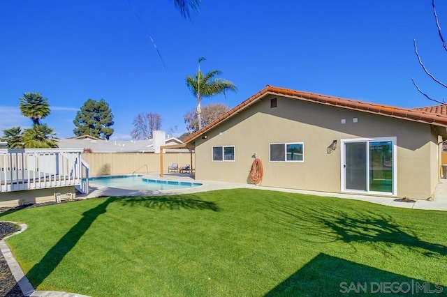 rear view of property featuring a pool side deck and a yard