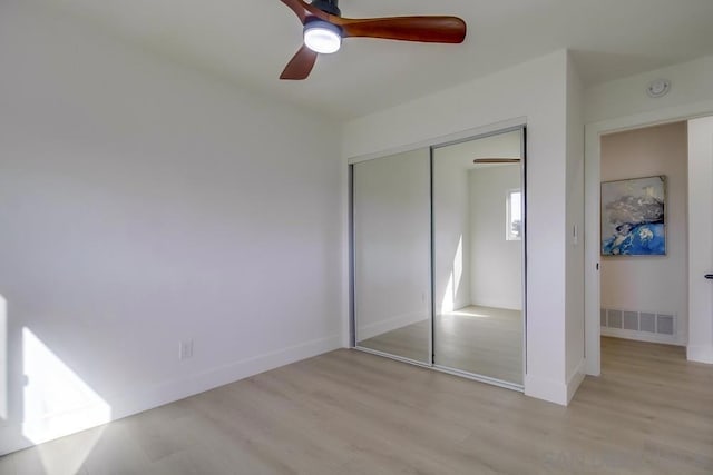 unfurnished bedroom with light hardwood / wood-style flooring, ceiling fan, and a closet