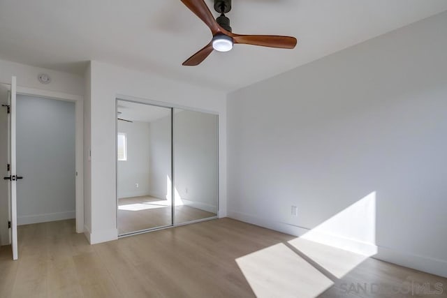 unfurnished bedroom featuring ceiling fan, a closet, and light wood-type flooring