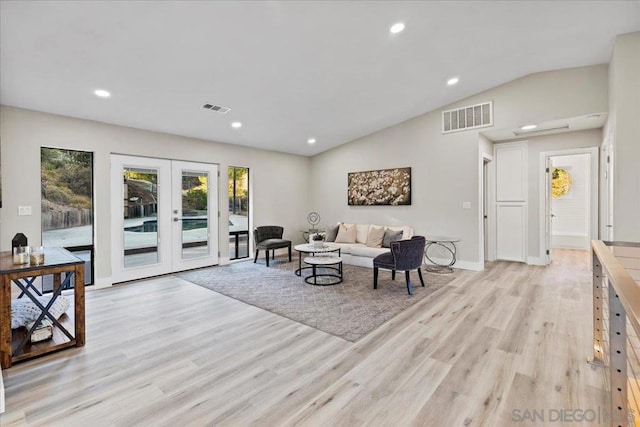 living room with french doors, vaulted ceiling, and light wood-type flooring