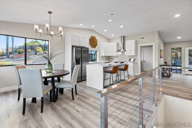 dining room featuring lofted ceiling, light hardwood / wood-style floors, and a chandelier