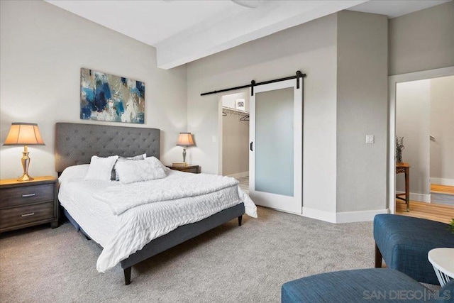 bedroom featuring a closet, a walk in closet, a barn door, and carpet flooring