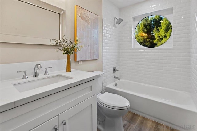 full bathroom with vanity, tiled shower / bath combo, wood-type flooring, and toilet