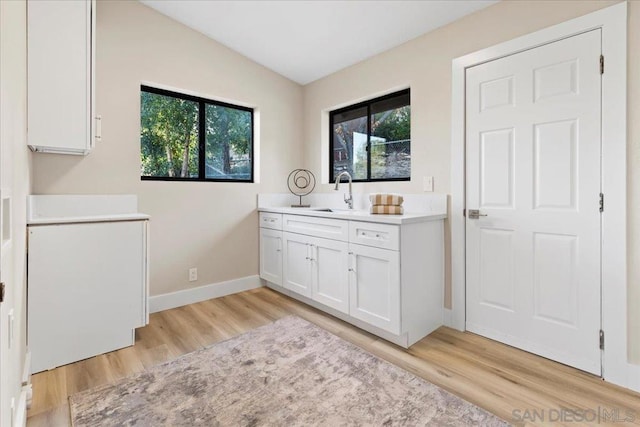 laundry area with plenty of natural light, sink, and light hardwood / wood-style floors