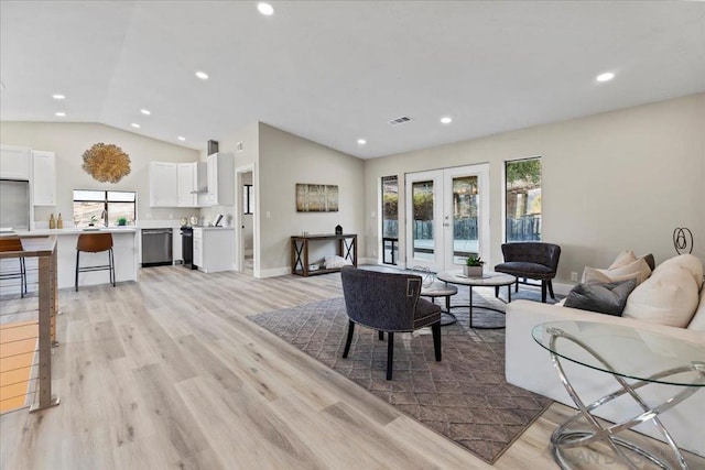 living room with french doors, lofted ceiling, sink, and light wood-type flooring