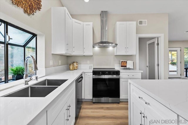 kitchen featuring sink, white cabinetry, plenty of natural light, stainless steel range with electric cooktop, and wall chimney exhaust hood