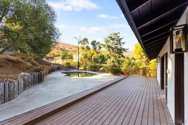 wooden terrace with a fenced in pool and a patio area