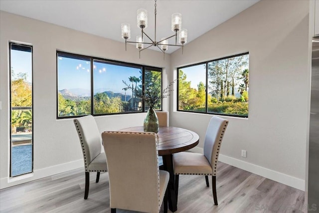 dining room with lofted ceiling, a mountain view, a notable chandelier, and light hardwood / wood-style flooring