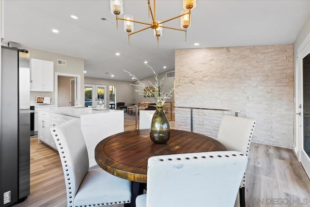 dining room featuring light hardwood / wood-style flooring, french doors, a chandelier, and vaulted ceiling