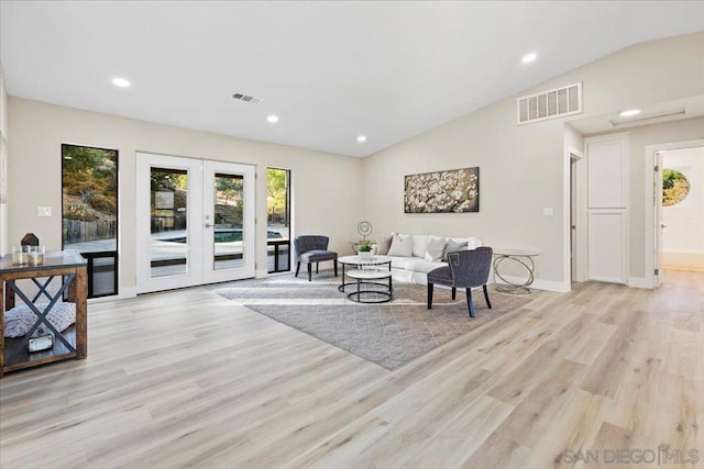 living room with vaulted ceiling, light hardwood / wood-style floors, and french doors