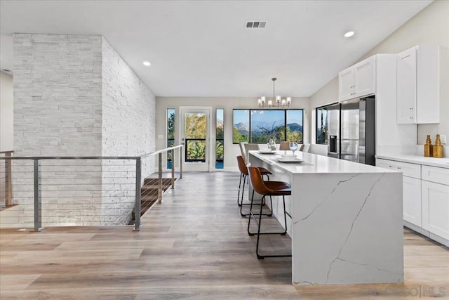 kitchen featuring white cabinetry, stainless steel fridge, decorative light fixtures, and a kitchen island