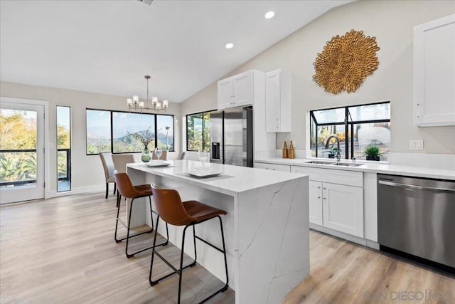 kitchen with appliances with stainless steel finishes, decorative light fixtures, a kitchen island, and white cabinets