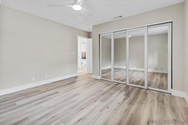 unfurnished bedroom with light hardwood / wood-style flooring, ceiling fan, and a closet