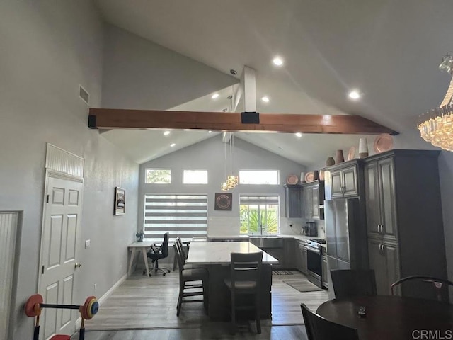 kitchen with a kitchen island, gray cabinetry, a kitchen bar, stainless steel range, and light stone counters