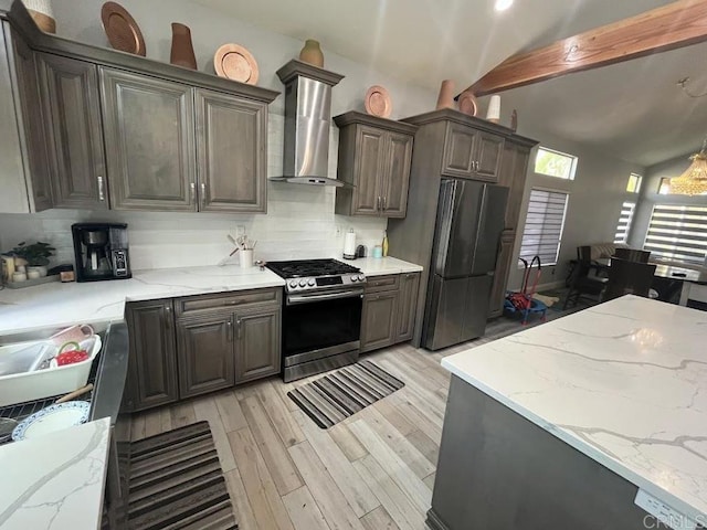 kitchen featuring wall chimney exhaust hood, light stone counters, light wood-type flooring, stainless steel appliances, and backsplash