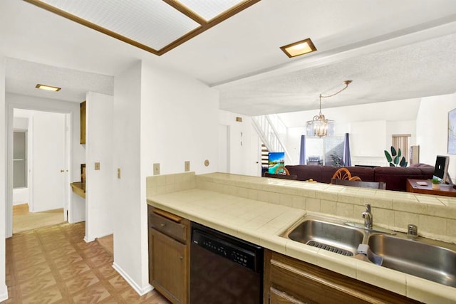 kitchen featuring sink, tile countertops, stainless steel dishwasher, and a chandelier