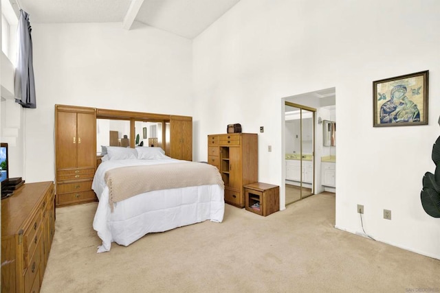 carpeted bedroom with ensuite bathroom, beam ceiling, and high vaulted ceiling