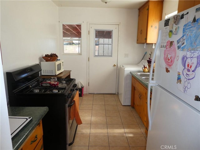 kitchen featuring light tile patterned flooring, white appliances, and independent washer and dryer