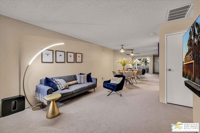 carpeted living room featuring ceiling fan and a textured ceiling