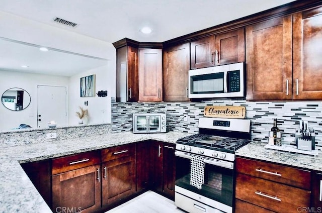 kitchen with stainless steel appliances, light stone countertops, and backsplash