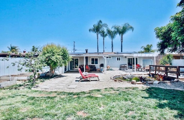 rear view of property featuring a yard and a patio area