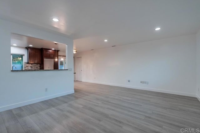 unfurnished living room featuring light wood-style flooring, baseboards, and recessed lighting