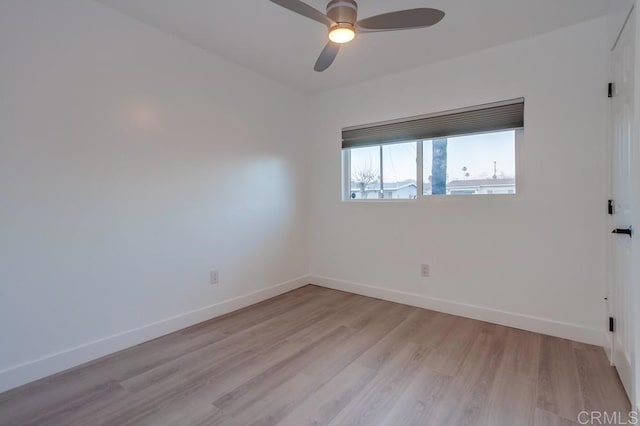 spare room featuring light wood finished floors, ceiling fan, and baseboards