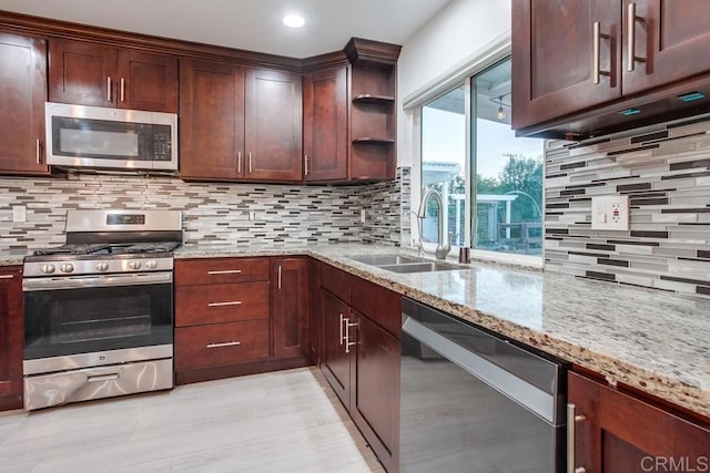 kitchen with tasteful backsplash, appliances with stainless steel finishes, light stone counters, open shelves, and a sink