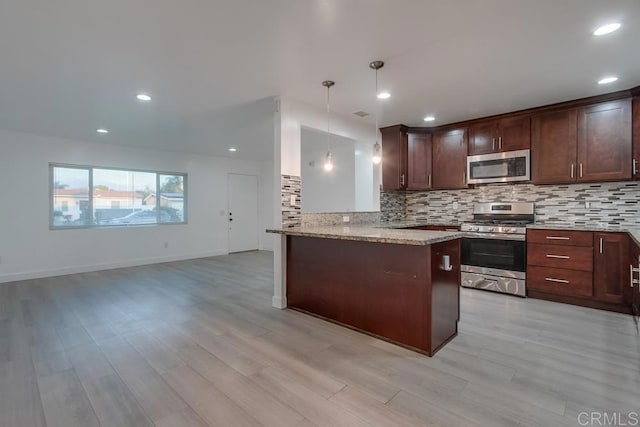 kitchen featuring appliances with stainless steel finishes, light stone counters, backsplash, and a peninsula