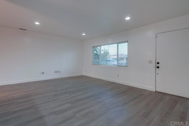 empty room featuring baseboards, wood finished floors, and recessed lighting