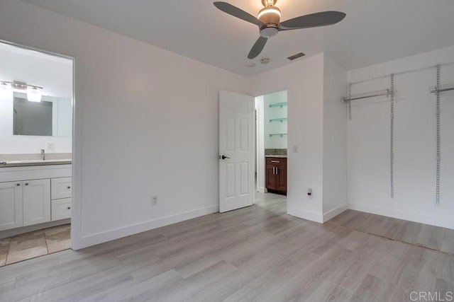 unfurnished bedroom with light wood-type flooring, visible vents, connected bathroom, and a sink