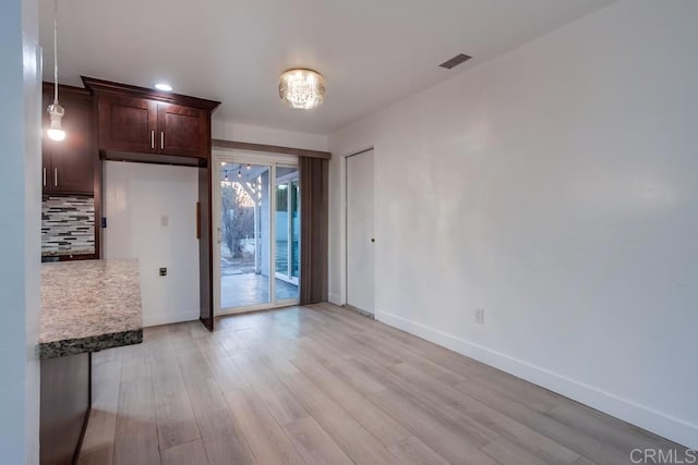 empty room with baseboards, visible vents, and light wood finished floors