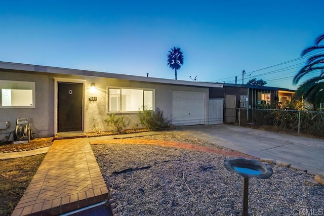 view of front facade featuring a garage, driveway, fence, and stucco siding