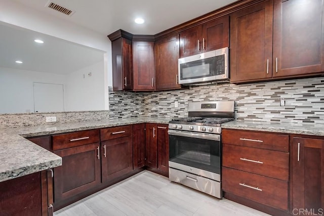 kitchen with light stone counters, recessed lighting, visible vents, appliances with stainless steel finishes, and backsplash