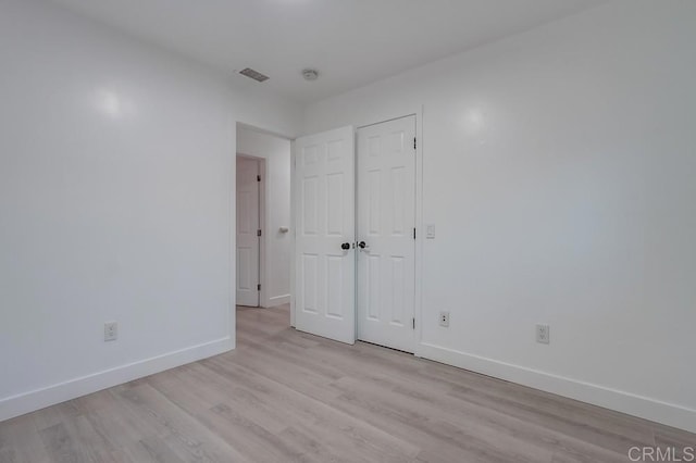 unfurnished bedroom featuring light wood-type flooring, visible vents, baseboards, and a closet