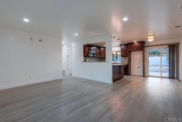 unfurnished living room featuring recessed lighting, baseboards, and light wood finished floors