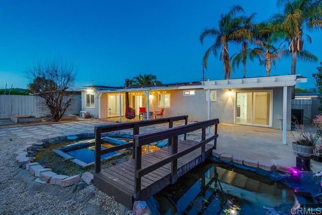 rear view of house featuring french doors, stucco siding, roof mounted solar panels, a patio area, and fence