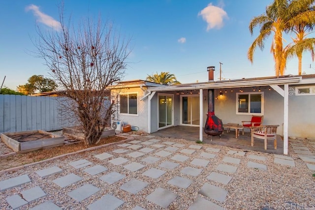 rear view of property with a patio, fence, and stucco siding