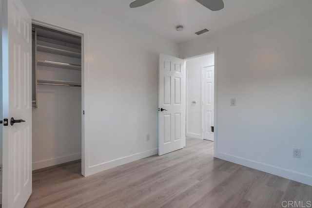 unfurnished bedroom featuring a closet, visible vents, a ceiling fan, wood finished floors, and baseboards