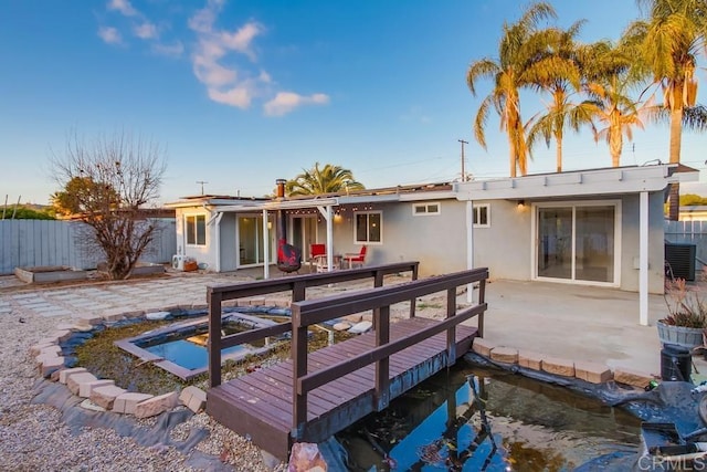 back of house with solar panels, a patio area, a fenced backyard, and stucco siding