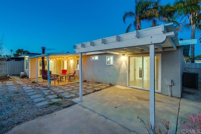 rear view of property with a patio area, fence, and stucco siding